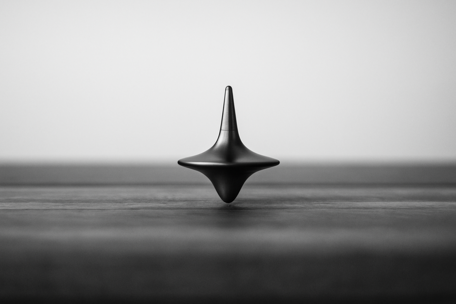 Schwarz-weiß-Fotografie eines sich drehenden Metallkreisels auf einer glatten Oberfläche.Das Bild symbolisiert Stabilität in Bewegung, innere Ordnung und die Energie regulierter Systeme – zentrale Prinzipien von Mindful Power und Neuro-Leadership.